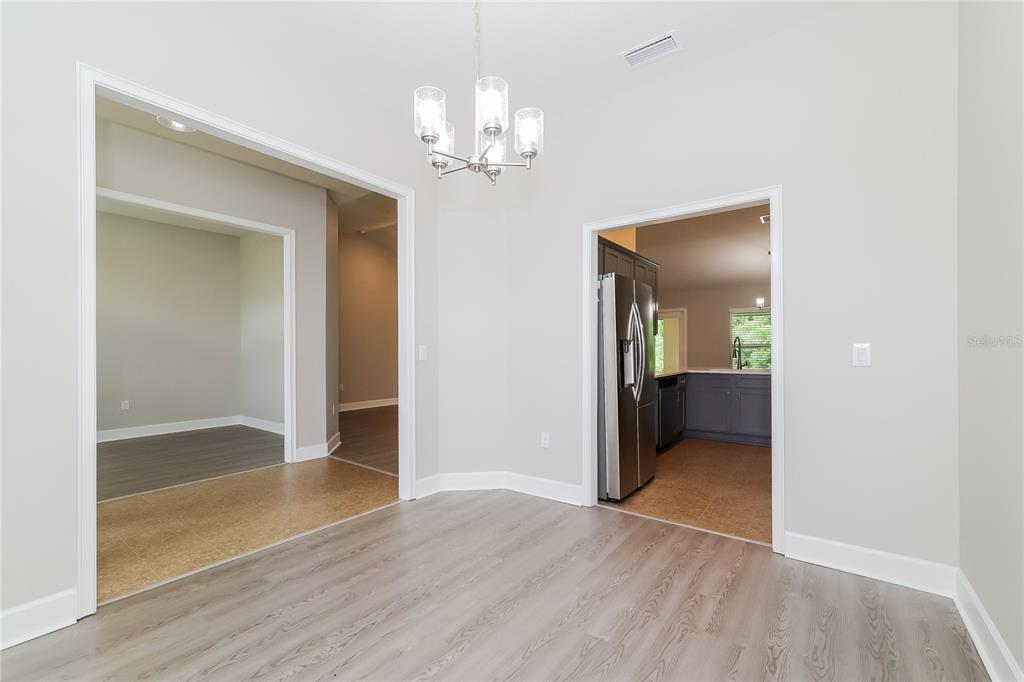 A dining area with light wood-look flooring, a chandelier, and doorways leading to other rooms — 345 CIMARRON COURT, POINCIANA, FL
