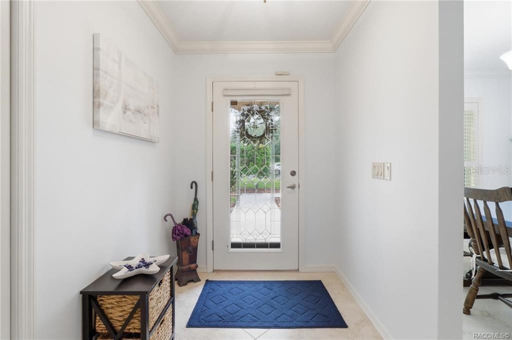 A bright entryway features a white front door with decorative glass, tile flooring, and furniture — 5983 W DOUNERAY LOOP, CRYSTAL RIVER, FL