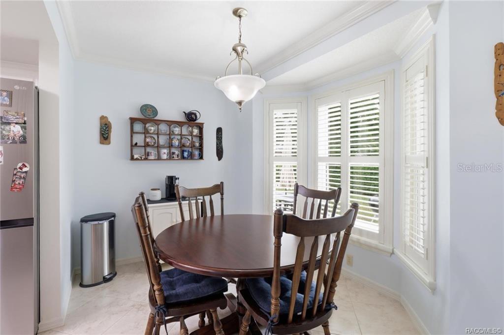 A dining area features a round wooden table, four chairs, a wall-mounted shelf, and shutters — 5983 W DOUNERAY LOOP, CRYSTAL RIVER, FL