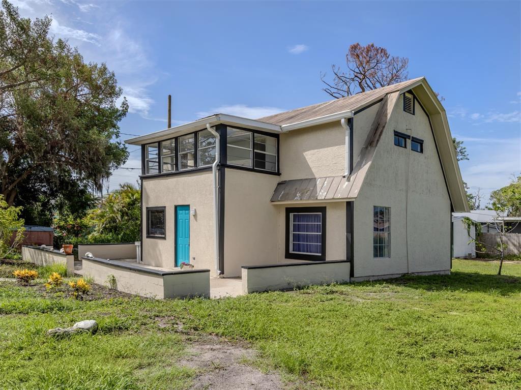 A two-story house with a gambrel roof, stucco exterior, and a bright blue front door — 305 CHAUNCEY AVENUE, BRADENTON, FL