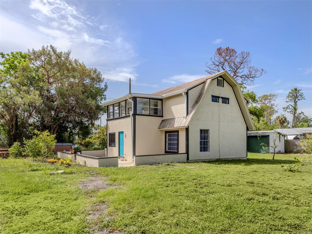 A two-story house with a gambrel roof sits on a grassy lot with trees — 305 CHAUNCEY AVENUE, BRADENTON, FL