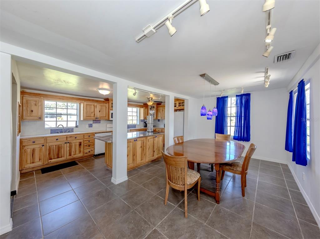 A dining area with a wooden table and chairs adjacent to a kitchen with wood cabinets — 305 CHAUNCEY AVENUE, BRADENTON, FL