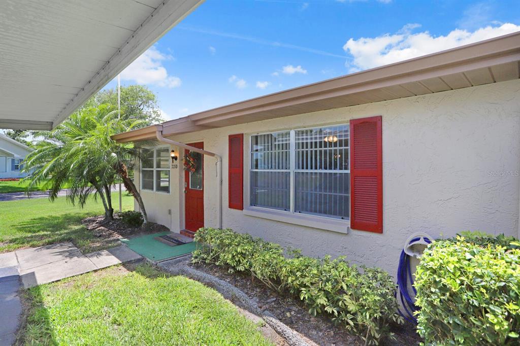A single-story house exterior features a red front door, red shutters, and a palm tree — 2210 GREENHAVEN DRIVE UNIT 375, SUN CITY CENTER, FL