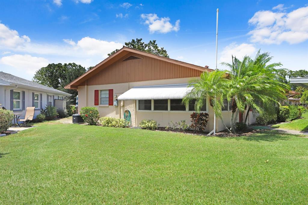 A single-story house with a tan exterior, brown gable siding, and a white metal awning — 2210 GREENHAVEN DRIVE UNIT 375, SUN CITY CENTER, FL