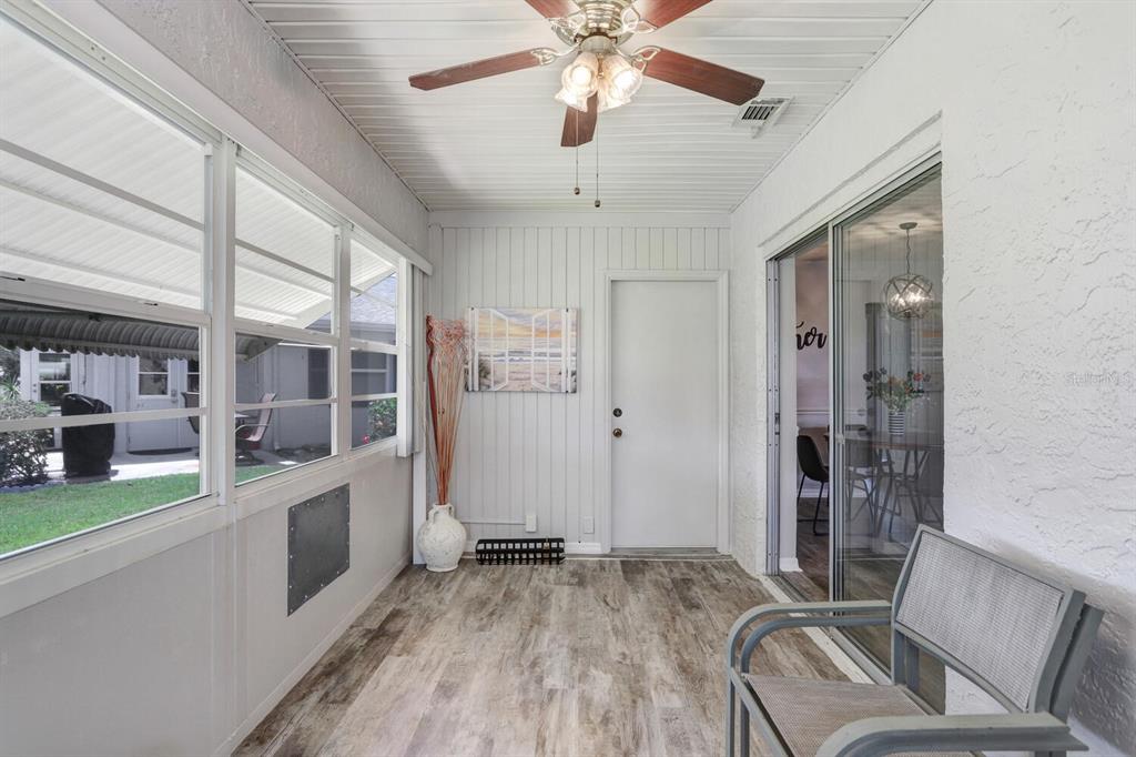 A sunroom features wood-look flooring, a ceiling fan, a white door, and sliding glass doors — 2210 GREENHAVEN DRIVE UNIT 375, SUN CITY CENTER, FL
