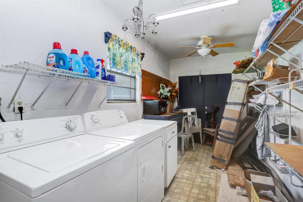 A laundry room features white appliances, wire shelving, a ceiling fan, and vinyl flooring — 2210 GREENHAVEN DRIVE UNIT 375, SUN CITY CENTER, FL