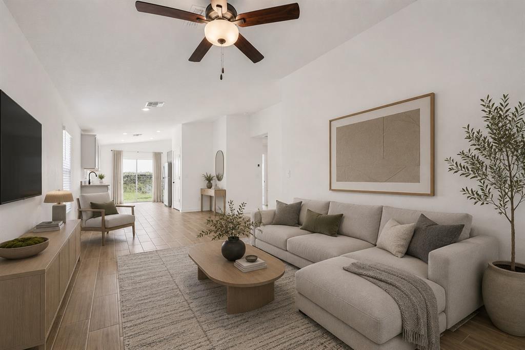A bright living room features a sectional sofa, wood-look tile flooring, and a ceiling fan — 5450 PARNELL AVENUE, SPRING HILL, FL