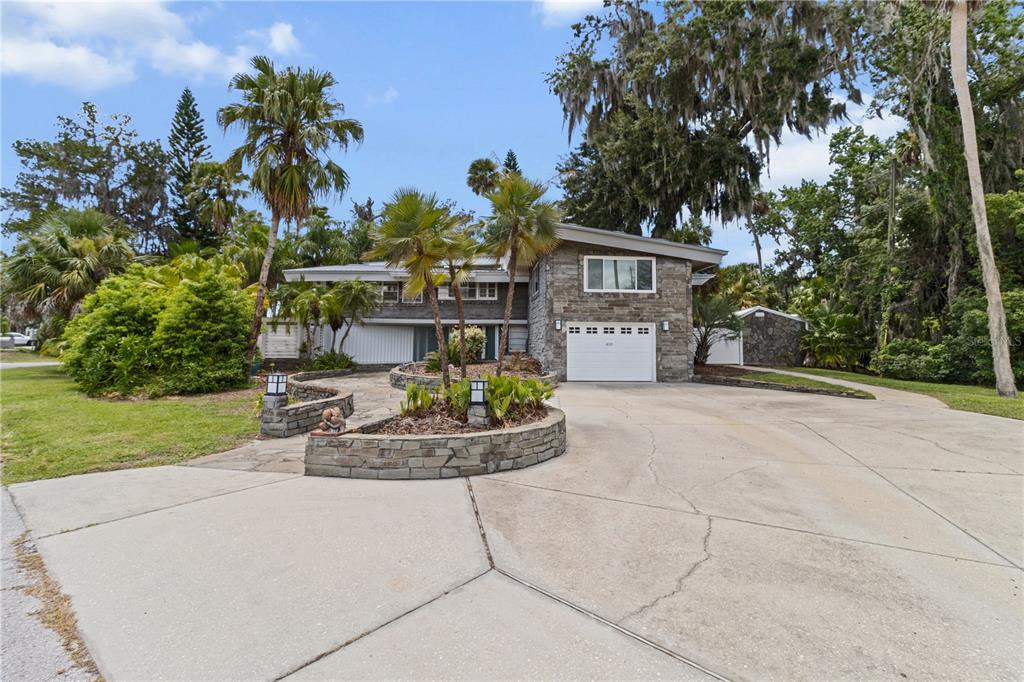 A two-story house with a stone facade, a white garage door, and a paved driveway — 1830 SE 3RD COURT, CRYSTAL RIVER, FL