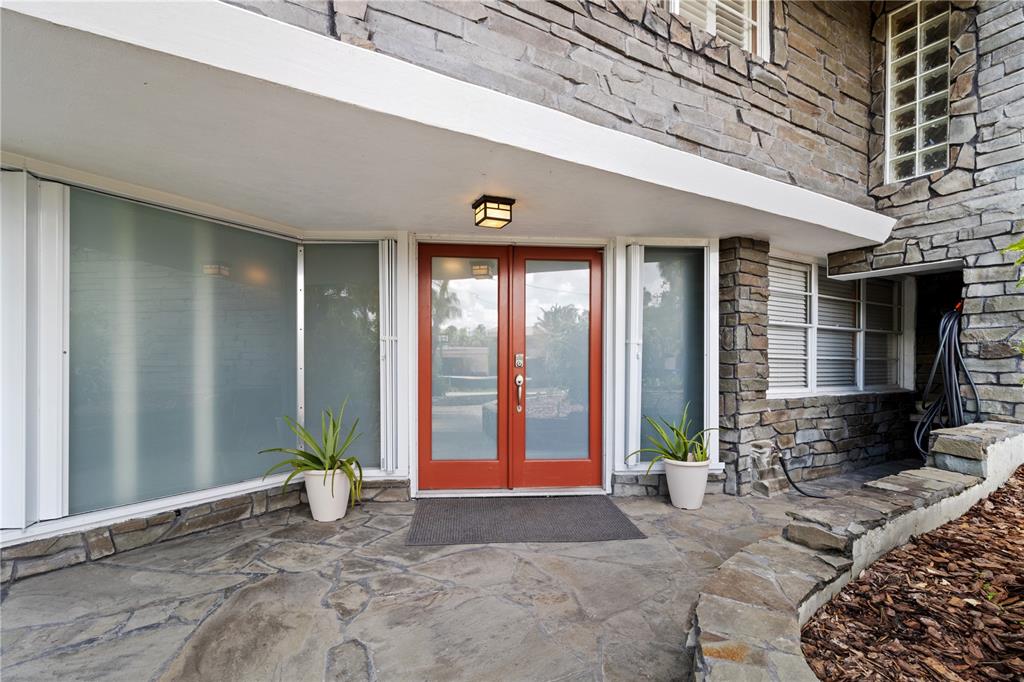 A stone-clad house exterior features a red double front door under a white overhang — 1830 SE 3RD COURT, CRYSTAL RIVER, FL