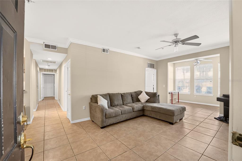 A living room features beige walls, tile flooring, a brown sectional sofa, and a coffee table — 2245 NW 16TH TERRACE UNIT 2245, GAINESVILLE, FL