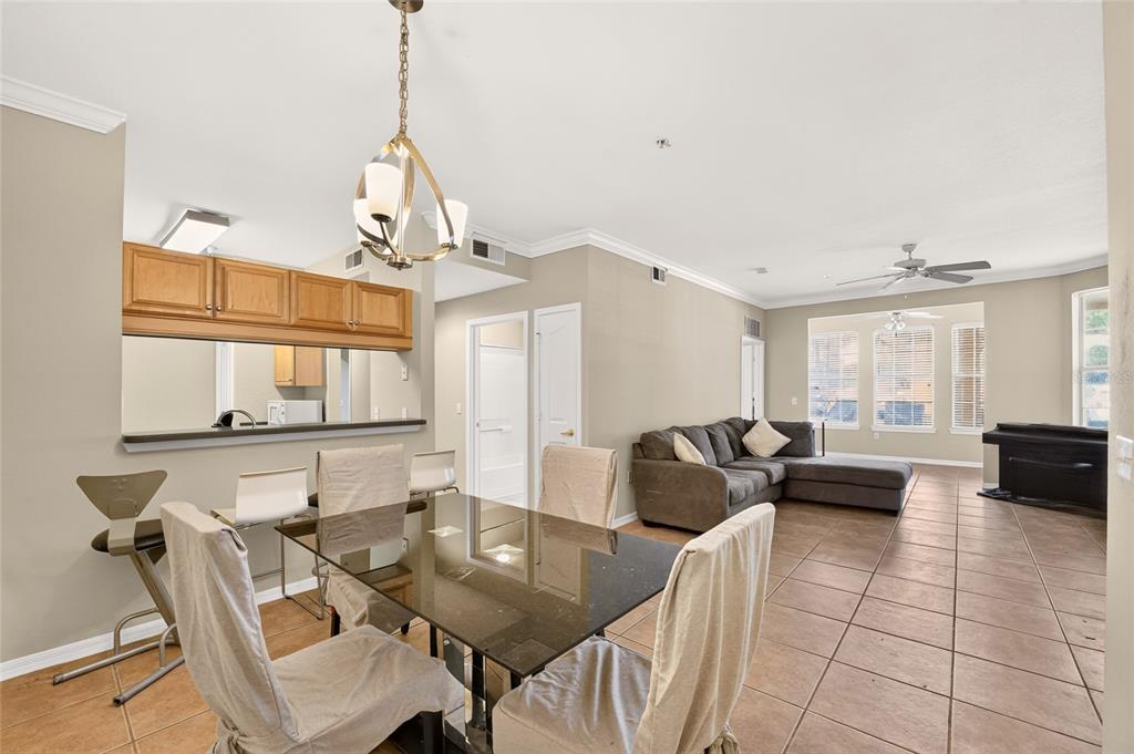 A dining area with a glass table and chairs opens to a living room with tile — 2245 NW 16TH TERRACE UNIT 2245, GAINESVILLE, FL