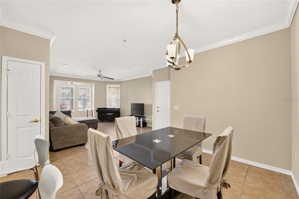 A dining area with a glass table and chairs opens into a living room space — 2245 NW 16TH TERRACE UNIT 2245, GAINESVILLE, FL