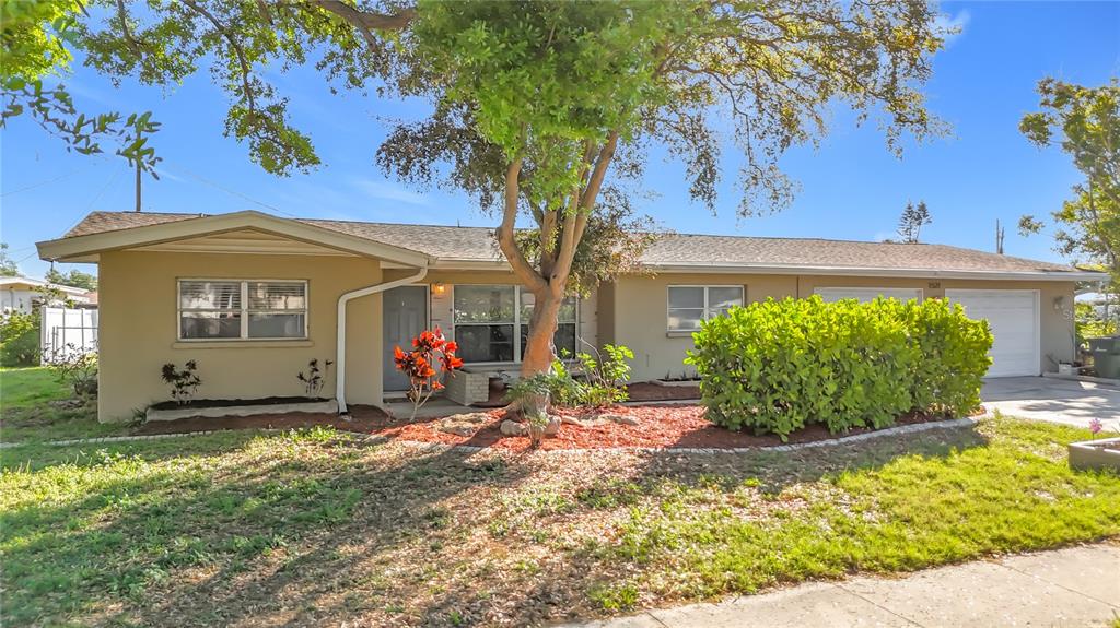 A single-story house with a tan exterior, a two-car garage, and a large front tree — 1521 BANYAN DR., VENICE, FL