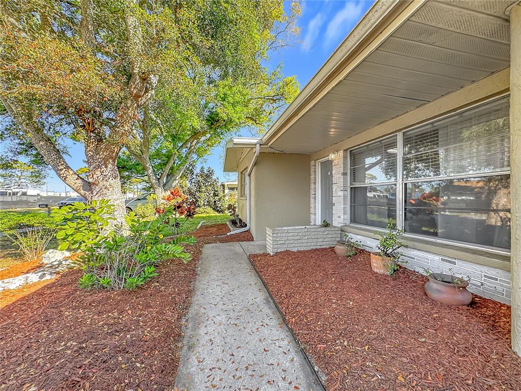 A concrete walkway leads to the front entrance of a house with tan siding — 1521 BANYAN DR., VENICE, FL