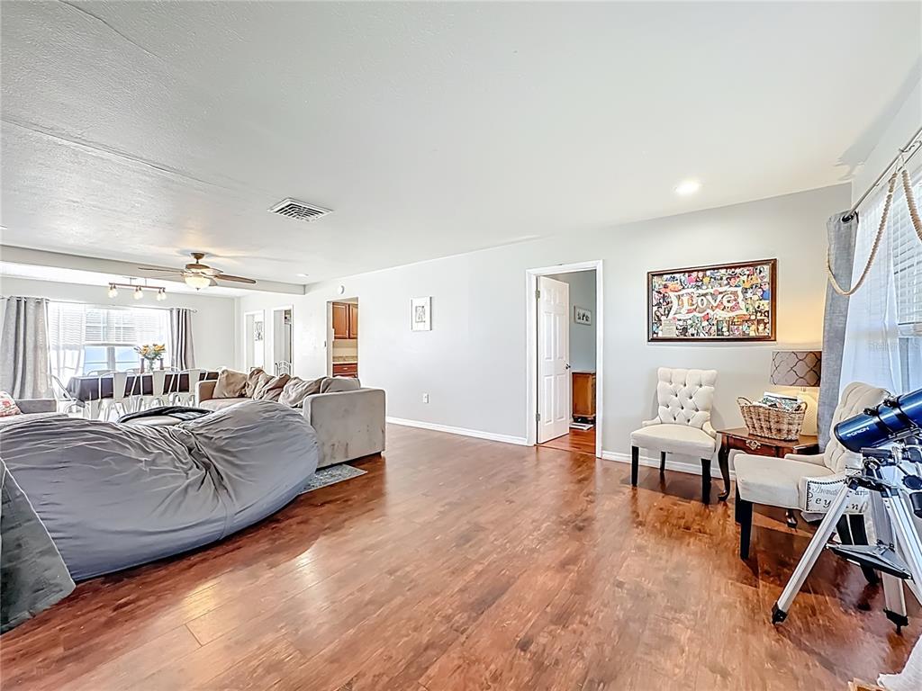 A living room with wood-look flooring, a large gray beanbag chair, and a telescope — 1521 BANYAN DR., VENICE, FL