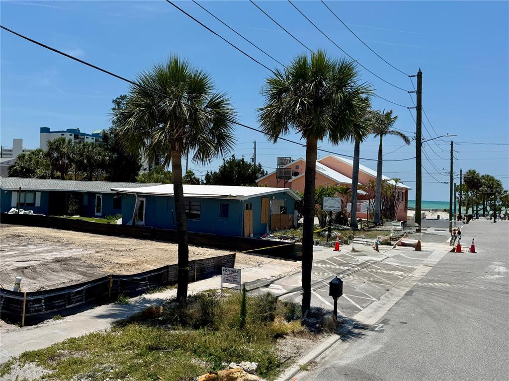 A vacant lot with a for-sale sign sits next to a blue house near the beach — 630 COREY AVENUE, ST PETE BEACH, FL