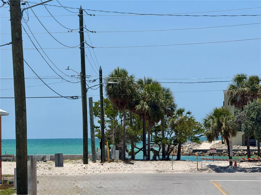 A view of a sandy beach area with palm trees, utility poles, and the ocean — 630 COREY AVENUE, ST PETE BEACH, FL