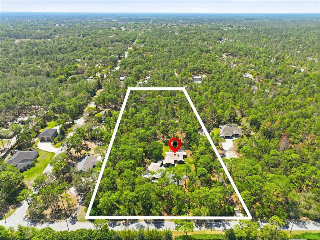 A screened-in patio features a swimming pool, lounge chairs, a grill, and a fire pit — 9032 BIRMINGHAM AVENUE, WEEKI WACHEE, FL