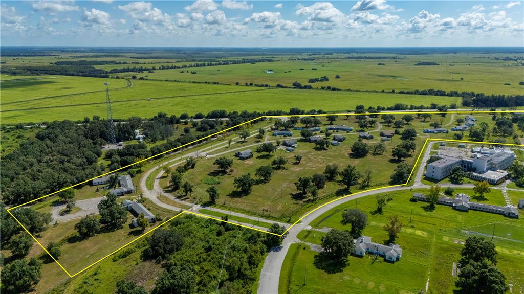 An aerial view shows a large property with multiple buildings, trees, and open fields — 6000 SE HWY 31, ARCADIA, FL
