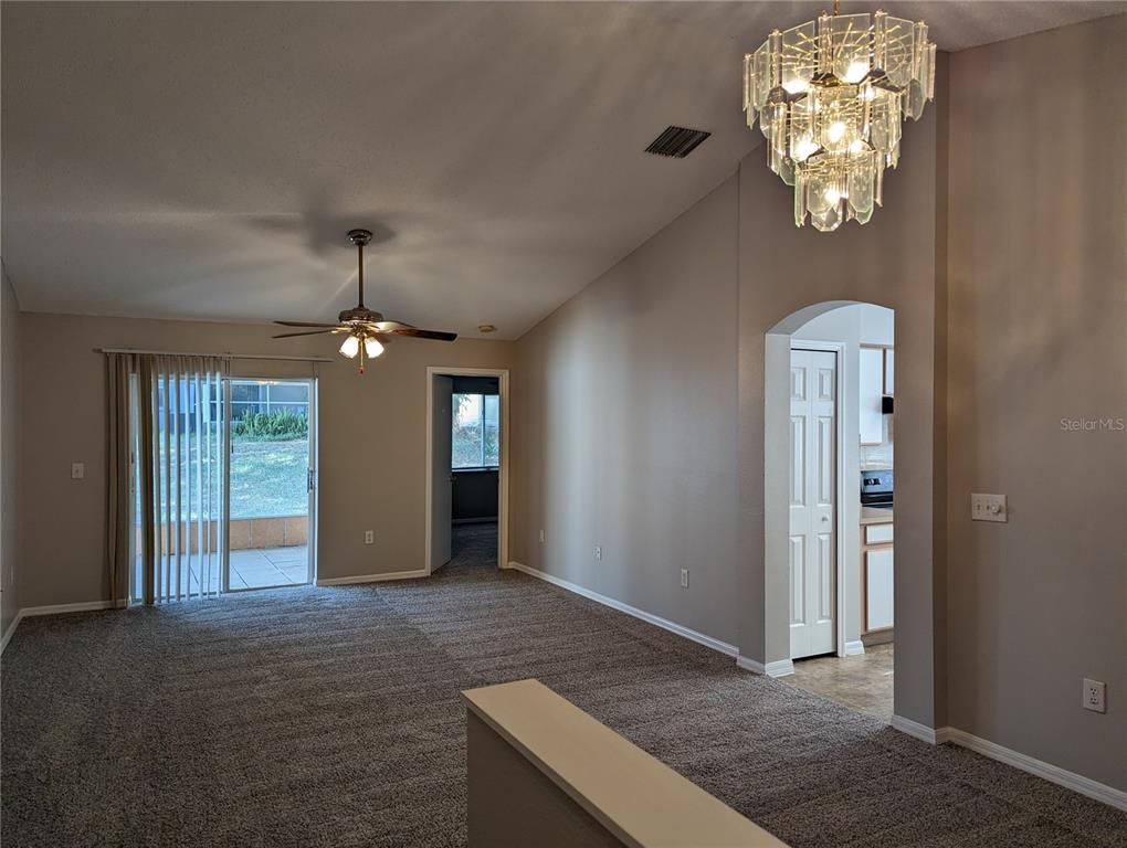 A living room with gray carpet, a vaulted ceiling, a ceiling fan, and a crystal chandelier — 3120 SUMMER HOUSE DRIVE, VALRICO, FL