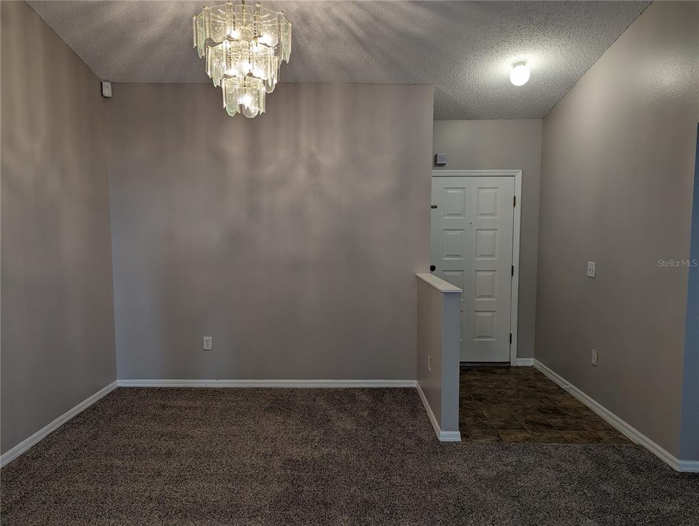 An entryway with tiled flooring leads into a carpeted room featuring a crystal chandelier — 3120 SUMMER HOUSE DRIVE, VALRICO, FL