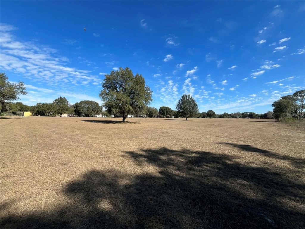 A wide, dry, grassy field under a blue sky with scattered clouds — 122-125 MILLER STREET, POMONA PARK, FL