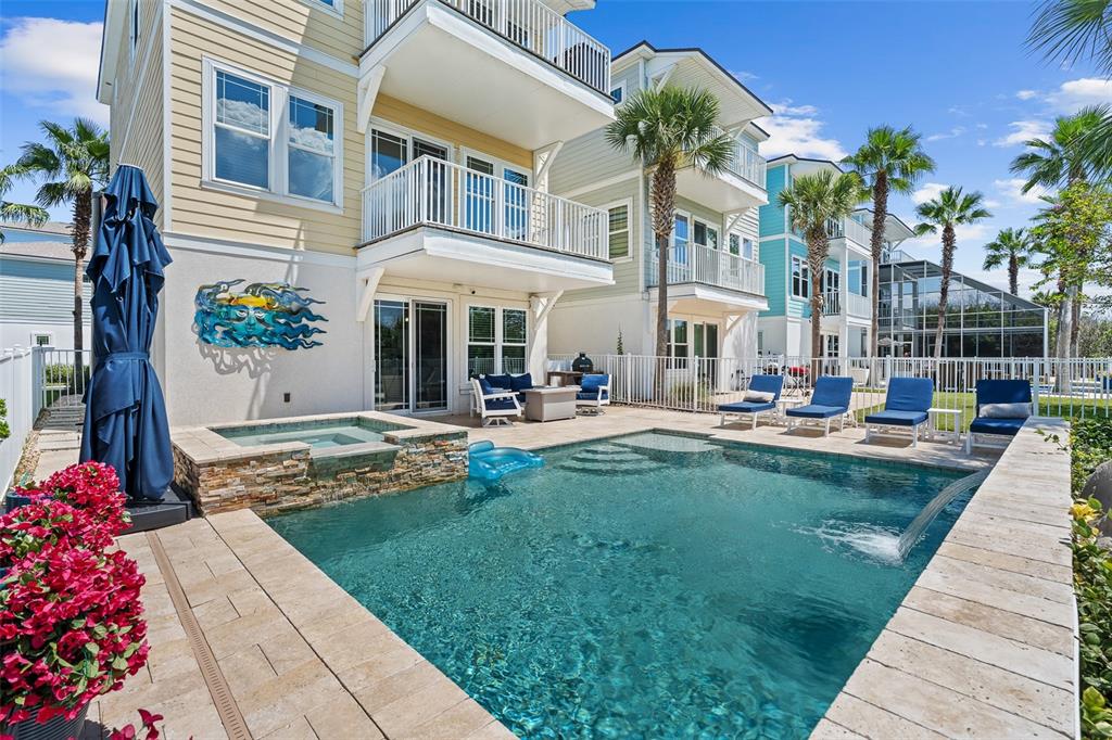 A backyard swimming pool and hot tub sit beside a multi-story house with balconies — 2770 MORNING LIGHT COURT, FLAGLER BEACH, FL