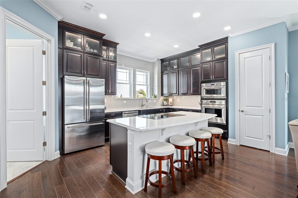 A kitchen with dark wood cabinets, a white island with seating, and stainless steel appliances — 2770 MORNING LIGHT COURT, FLAGLER BEACH, FL