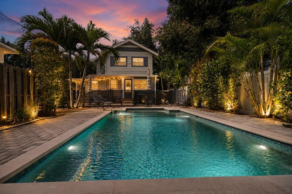A backyard swimming pool sits in front of a two-story house at sunset — 857 21ST AVENUE N, ST PETERSBURG, FL