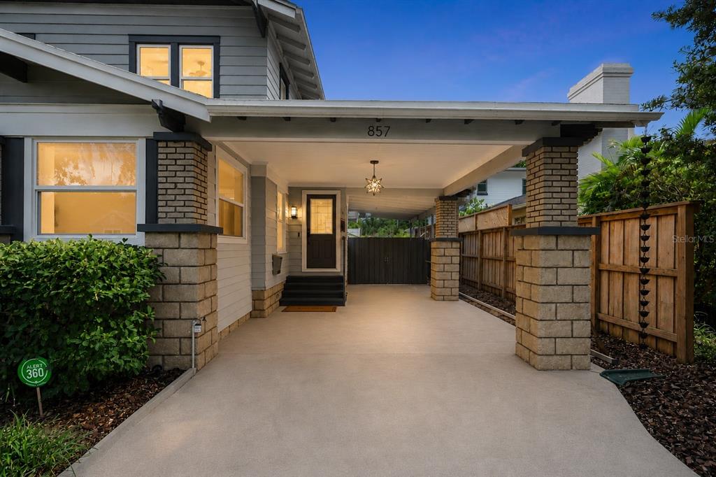 A covered carport leads to the front entrance of a gray house with brick pillars — 857 21ST AVENUE N, ST PETERSBURG, FL