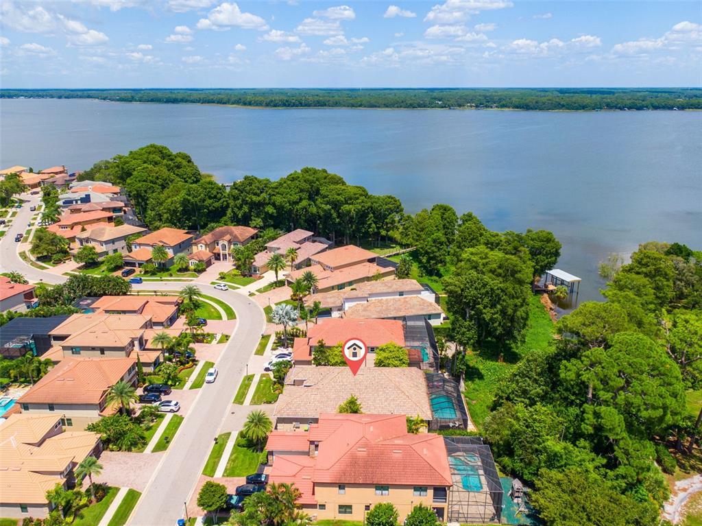 An aerial view shows a residential neighborhood with houses, swimming pools, and a large lake — 2622 GRAND LAKESIDE DRIVE, PALM HARBOR, FL