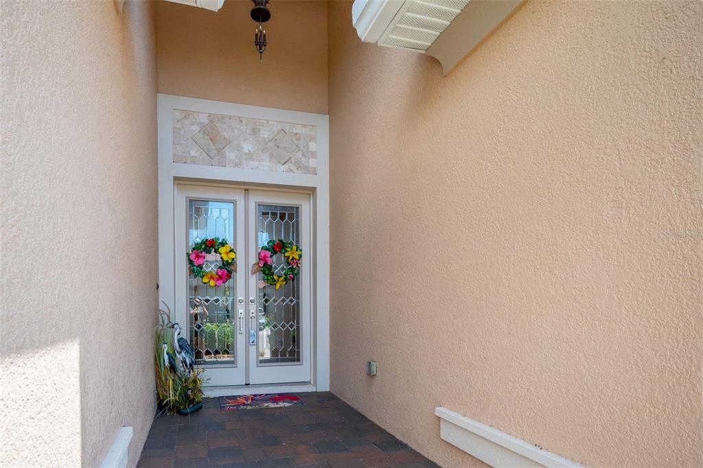 A covered entryway features double glass doors with floral wreaths and a tiled floor — 2622 GRAND LAKESIDE DRIVE, PALM HARBOR, FL