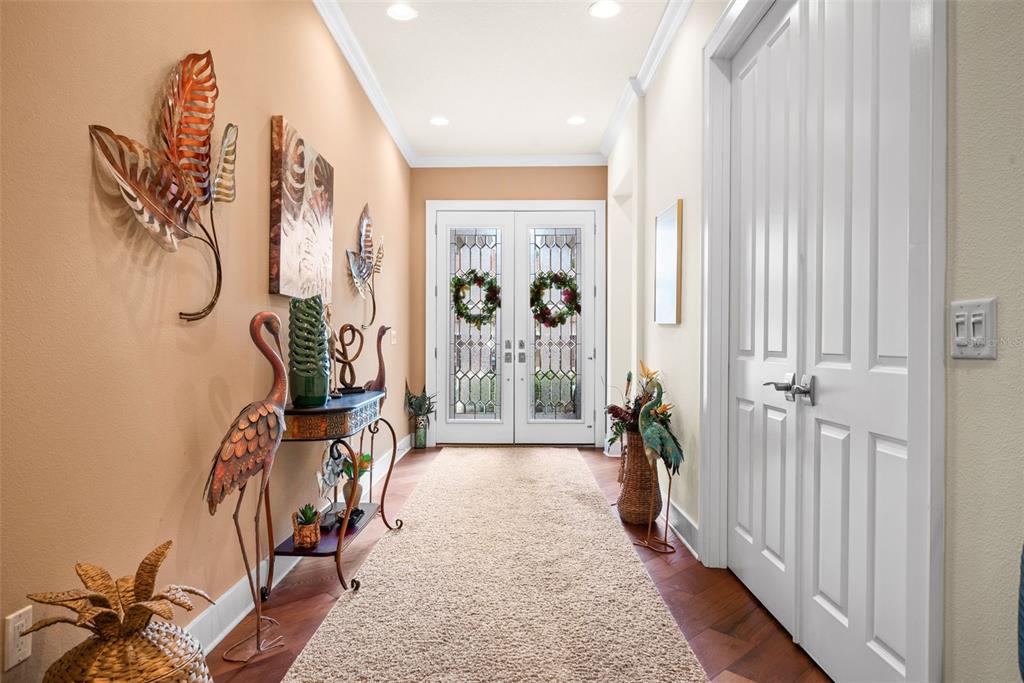 A bright entryway features a long runner rug, a console table, and double glass doors — 2622 GRAND LAKESIDE DRIVE, PALM HARBOR, FL