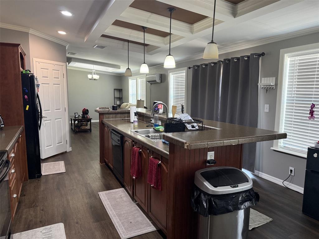 A kitchen features dark wood cabinets, a tiled island countertop, and pendant lighting — 12091 PINETREE LANE, BROOKSVILLE, FL