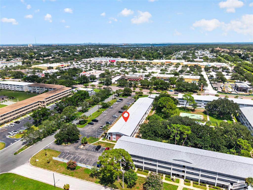An aerial view shows apartment buildings, a parking lot, and a nearby shopping center — 1000 79TH AVENUE N UNIT 111, ST PETERSBURG, FL