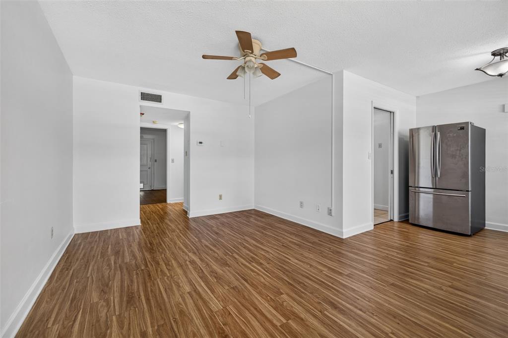 A room with wood-look flooring, a ceiling fan, and a stainless steel refrigerator — 1000 79TH AVENUE N UNIT 111, ST PETERSBURG, FL