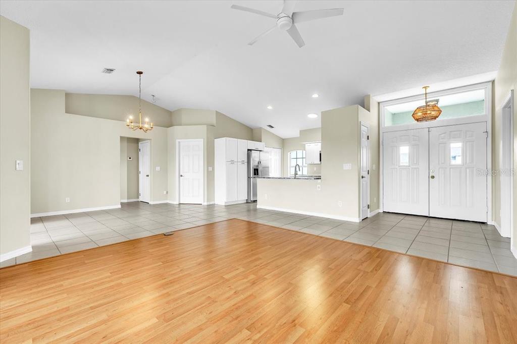An open-concept living area features wood flooring, tiled kitchen space, and a vaulted ceiling — 485 BOUNDARY BOULEVARD, ROTONDA WEST, FL