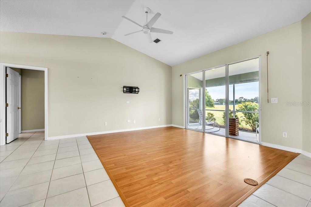 A living room features light-colored walls, tile and wood flooring, a ceiling fan, and sliding doors — 485 BOUNDARY BOULEVARD, ROTONDA WEST, FL