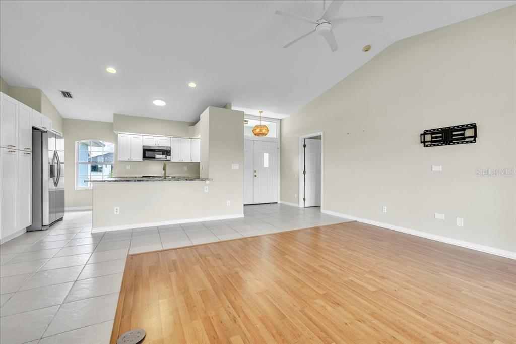 An open-concept living area features wood flooring, a tiled kitchen, and a vaulted ceiling — 485 BOUNDARY BOULEVARD, ROTONDA WEST, FL