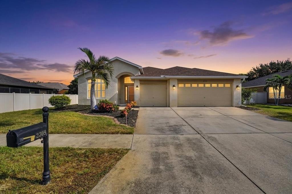 A single-story house with a beige stucco exterior, a three-car garage, and a palm tree — 2309 SWORDFISH AVENUE, HOLIDAY, FL