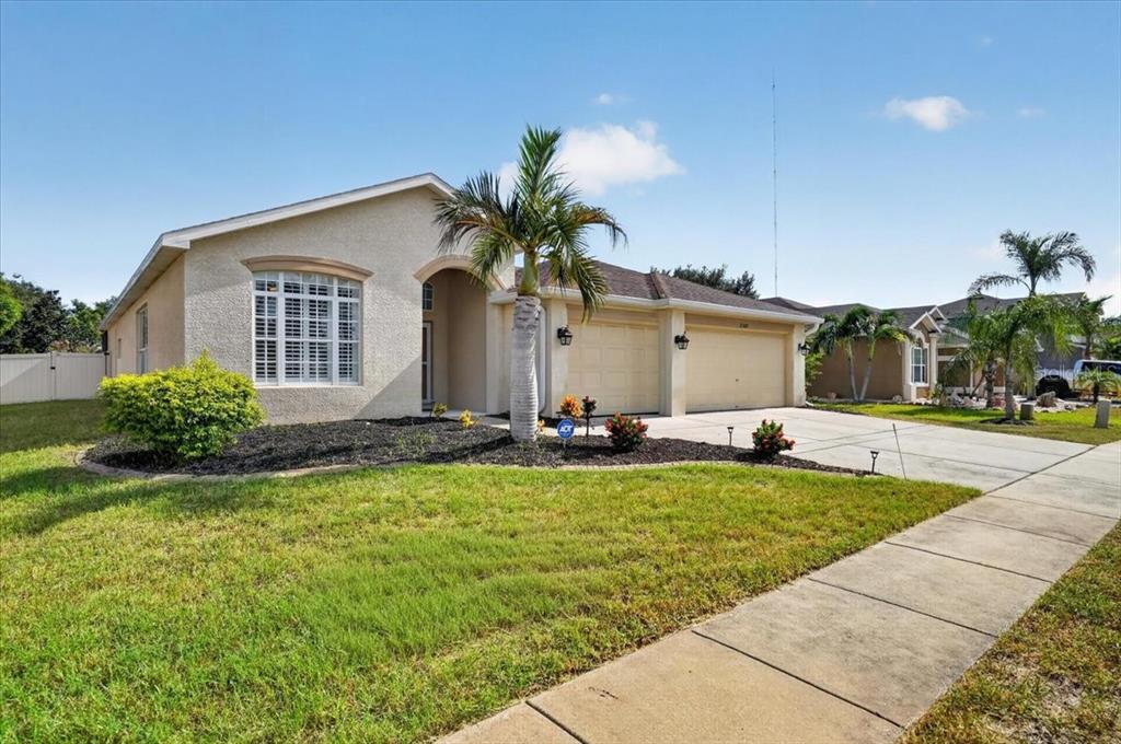 A single-story beige stucco house with a two-car garage and a palm tree in front — 2309 SWORDFISH AVENUE, HOLIDAY, FL