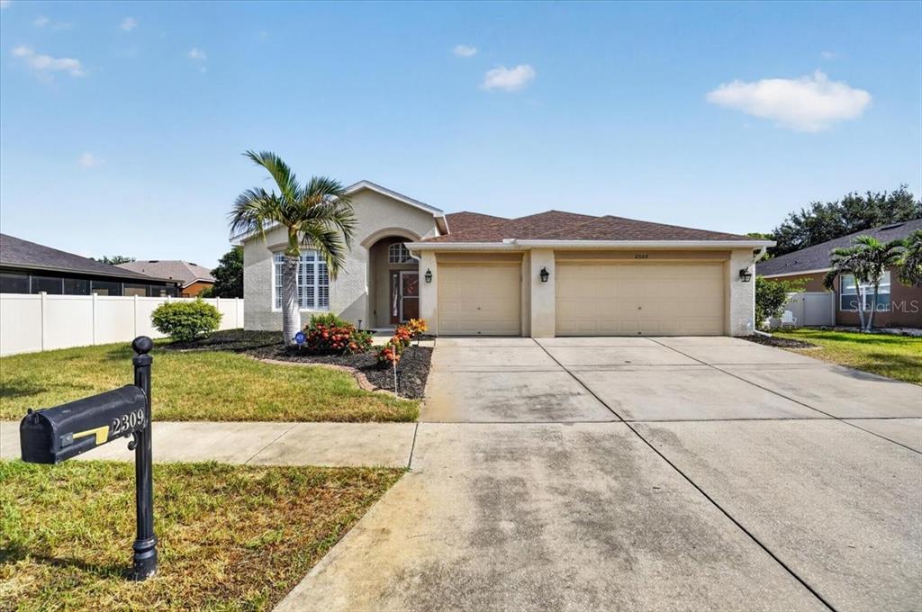A single-story house with a two-car garage, a palm tree, and a mailbox in front — 2309 SWORDFISH AVENUE, HOLIDAY, FL