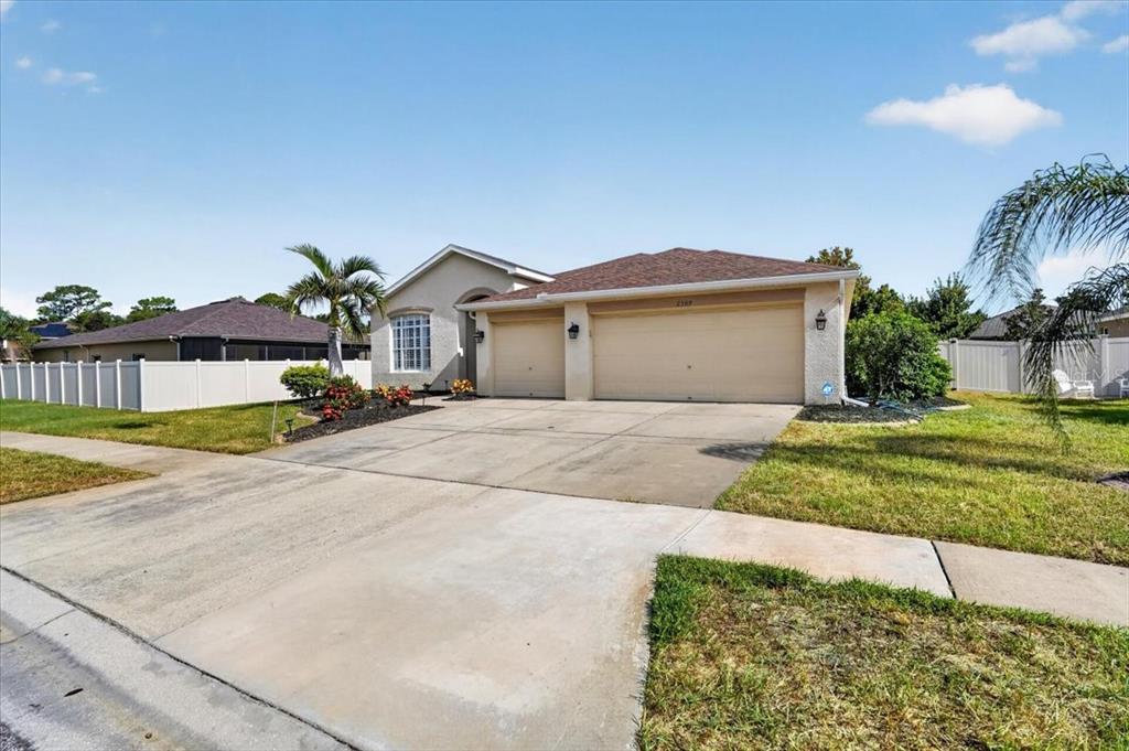 A single-story house with a beige stucco exterior, a three-car garage, and a concrete driveway — 2309 SWORDFISH AVENUE, HOLIDAY, FL