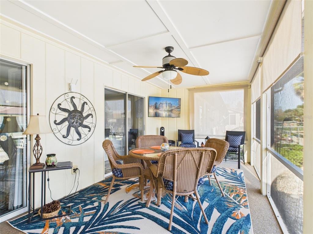 A screened-in patio features a wicker dining set, a ceiling fan, and a patterned rug — 4529 MERCADO DRIVE, SEBRING, FL