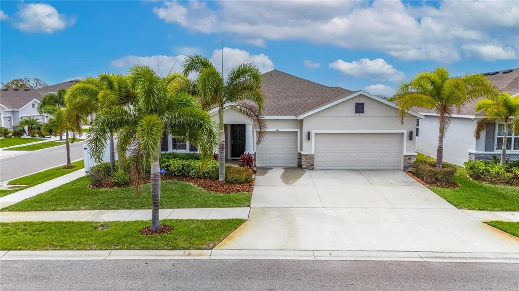 A single-story house with a three-car garage, palm trees, and a concrete driveway — 446 6TH AVENUE NW, RUSKIN, FL