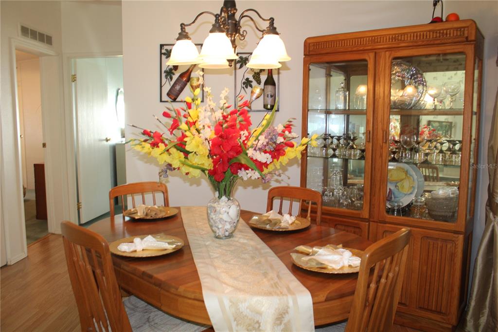A dining room features a wooden table, chairs, a floral centerpiece, and a glass-front china cabinet — 8314 NANCY LANE, ELLENTON, FL