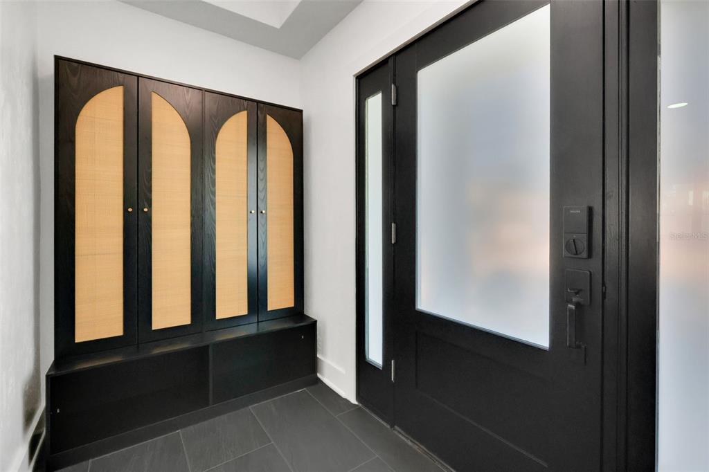 An entryway features a black storage unit with arched cane panels and a black door — 39 E PARK AVENUE, ST AUGUSTINE, FL