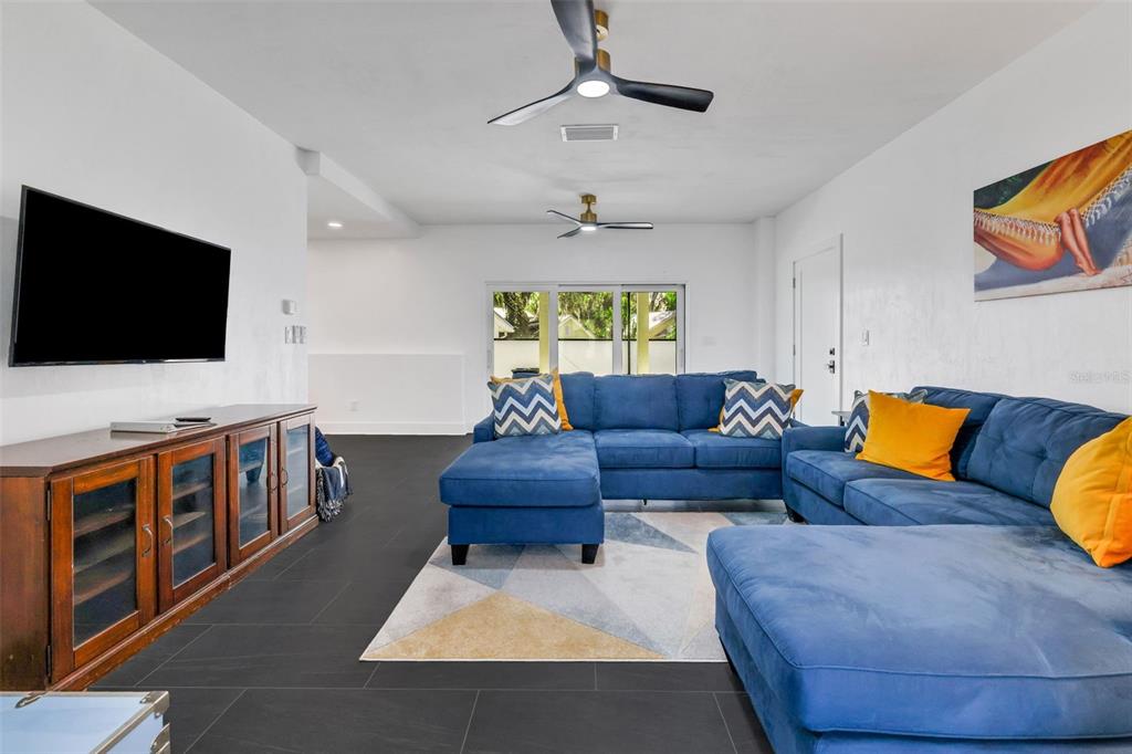 A living room features a blue sectional sofa, a television, and dark tile flooring — 39 E PARK AVENUE, ST AUGUSTINE, FL