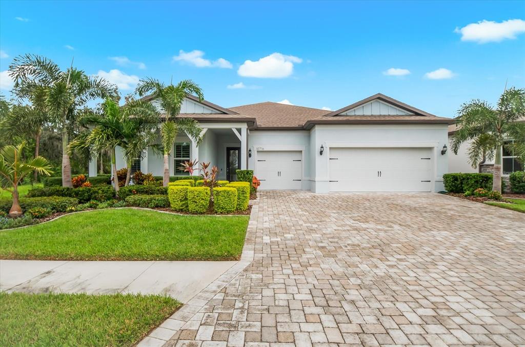 A single-story house with a paved driveway, three-car garage, and palm trees in the yard — 10716 SARATOGA PLACE, PARRISH, FL