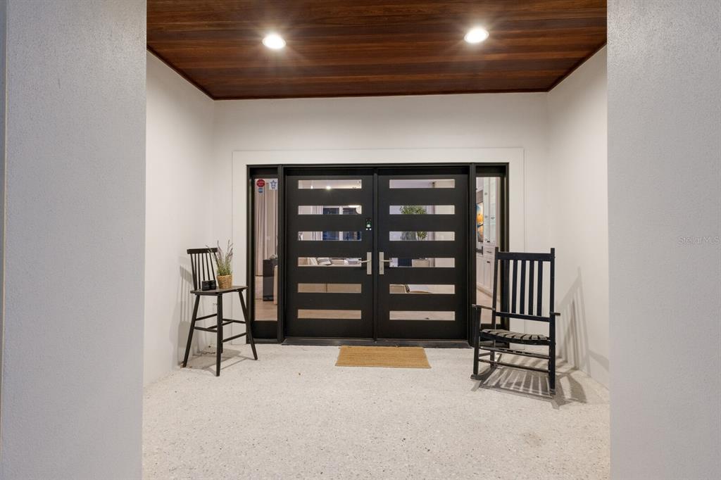 A covered entryway features a double front door, a wooden ceiling, and two black chairs — 238 ISLAND CIRCLE, SARASOTA, FL